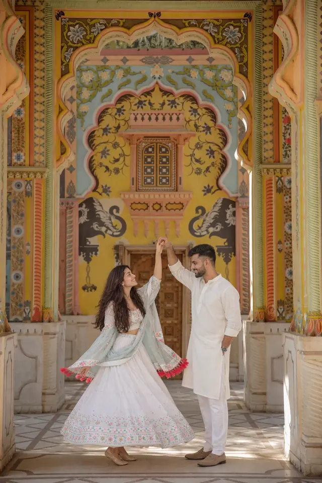 Twirling under painted arches: a couple photographed at Patrika Gate, Jaipur